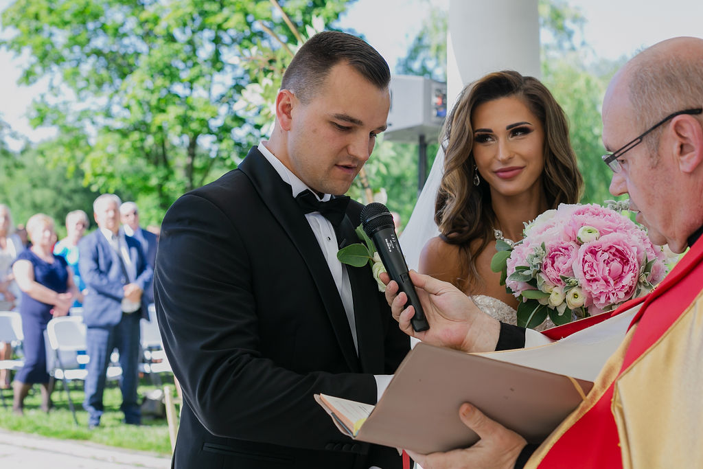 Bride Sylwia adjusting her veil while groom Paweł watches lovingly