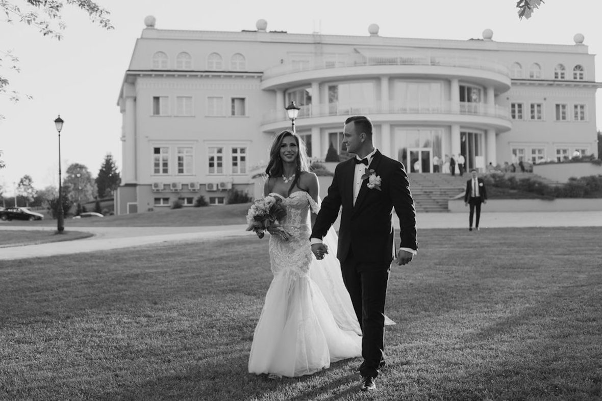 Sylwia and Paweł standing together smiling on their wedding day outdoors